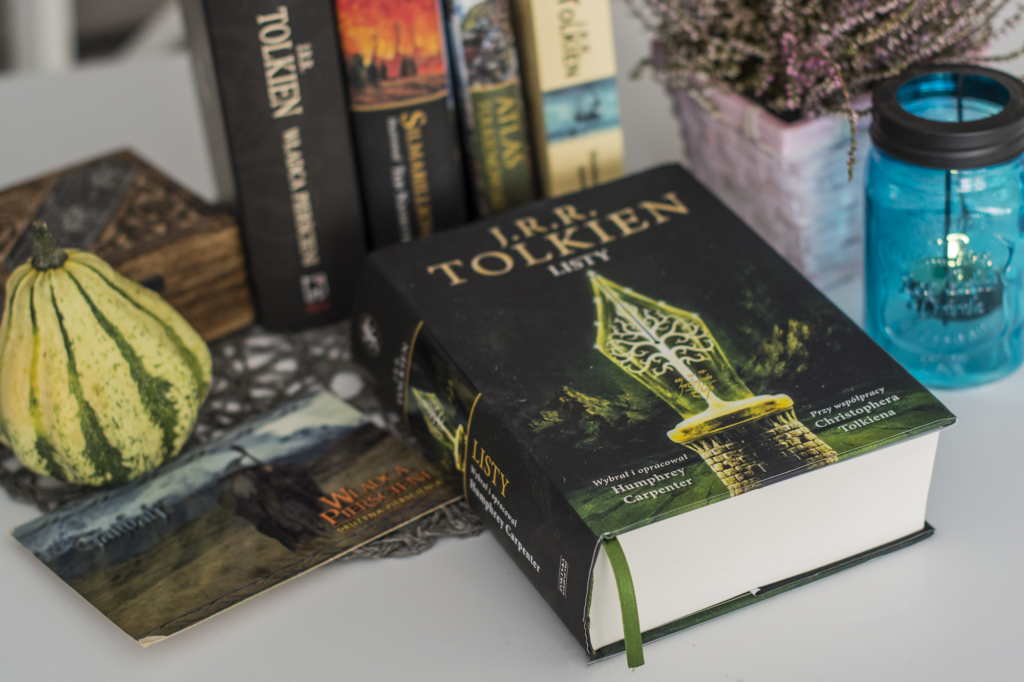 Listy J. R. R. Tolkien - książka lezy na blacie, w tle inne książki Tolkiena, książkę otacza lampion, wrzos w doniczce, tolkienowska pocztówka, dynia - recenzja książki z listami pisarza fantasy