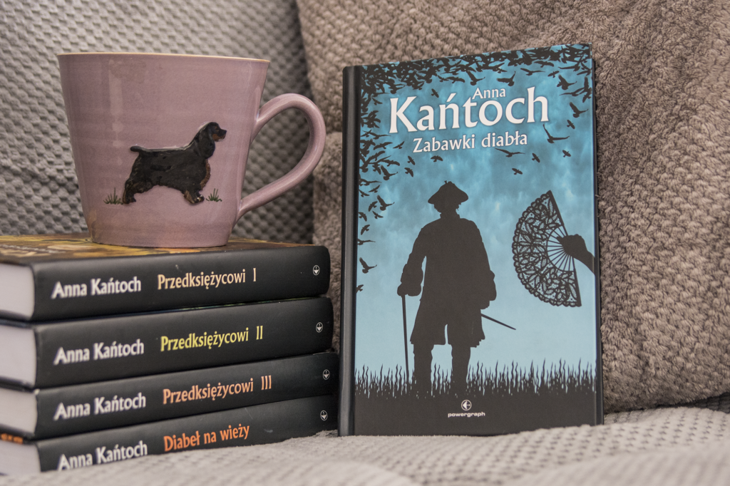 Zabawki diabła Anny Kańtoch - książka stoi na kanapie obok innych książek Anny Kańtoch - ilustracja do recenzji historycznego fantasy