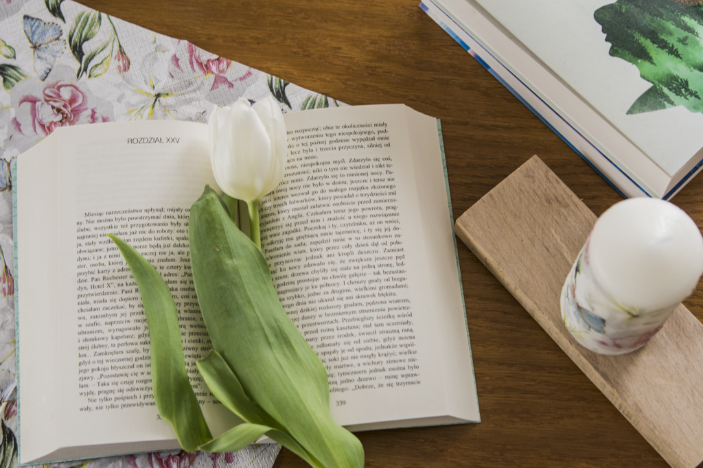Dziwne losy Jane Eyre Bronte - otwartu klasyk literatury leży na blacie wśród ozdób, biały tulipan pomiędzy kartkami