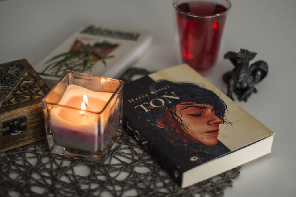 Toń Marty Kisiel - książka lezy na blacie w otoczeniu ozdób - ilustracje do recenzji wrocławskiego urban fantasy