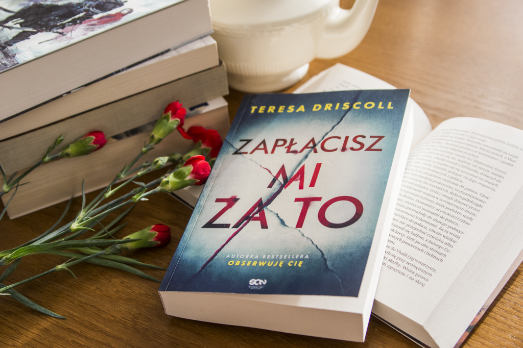 Zapłacisz mi za to Driscoll - ksiązka lezy na blacie w otoczeniu ozdób