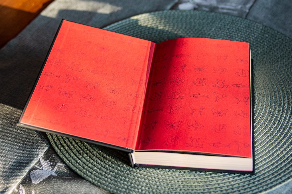 Papierowy Mag Charlie N. Holmberg - otwarta książka leży na blacie; widok na czerwoną wyklejkę z origami