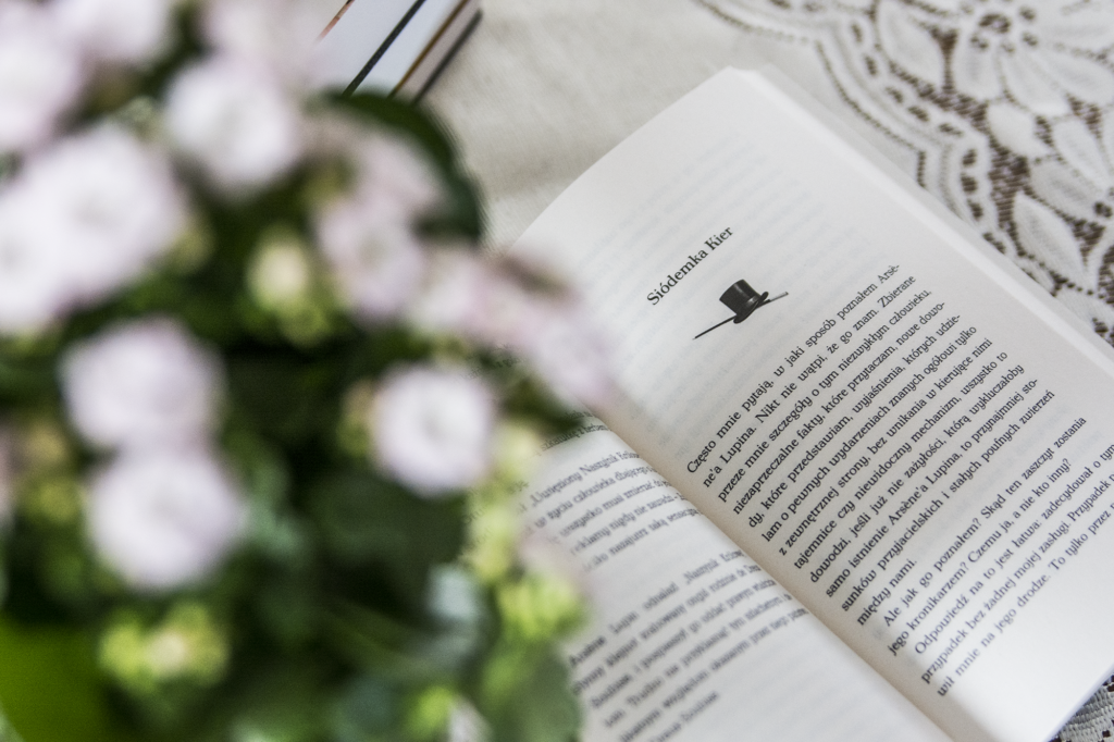 Dżentelmen włamywacz - otwarta książka leży na blacie wśród ozdób