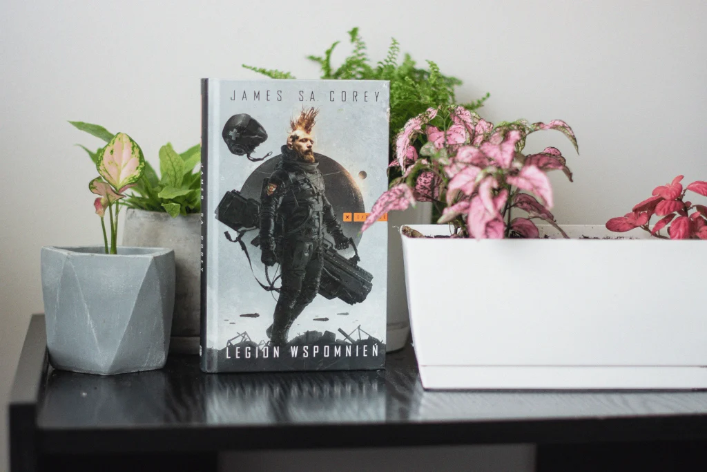 Legion wspomnień książka stoi wśród kwiatów doniczkowych
